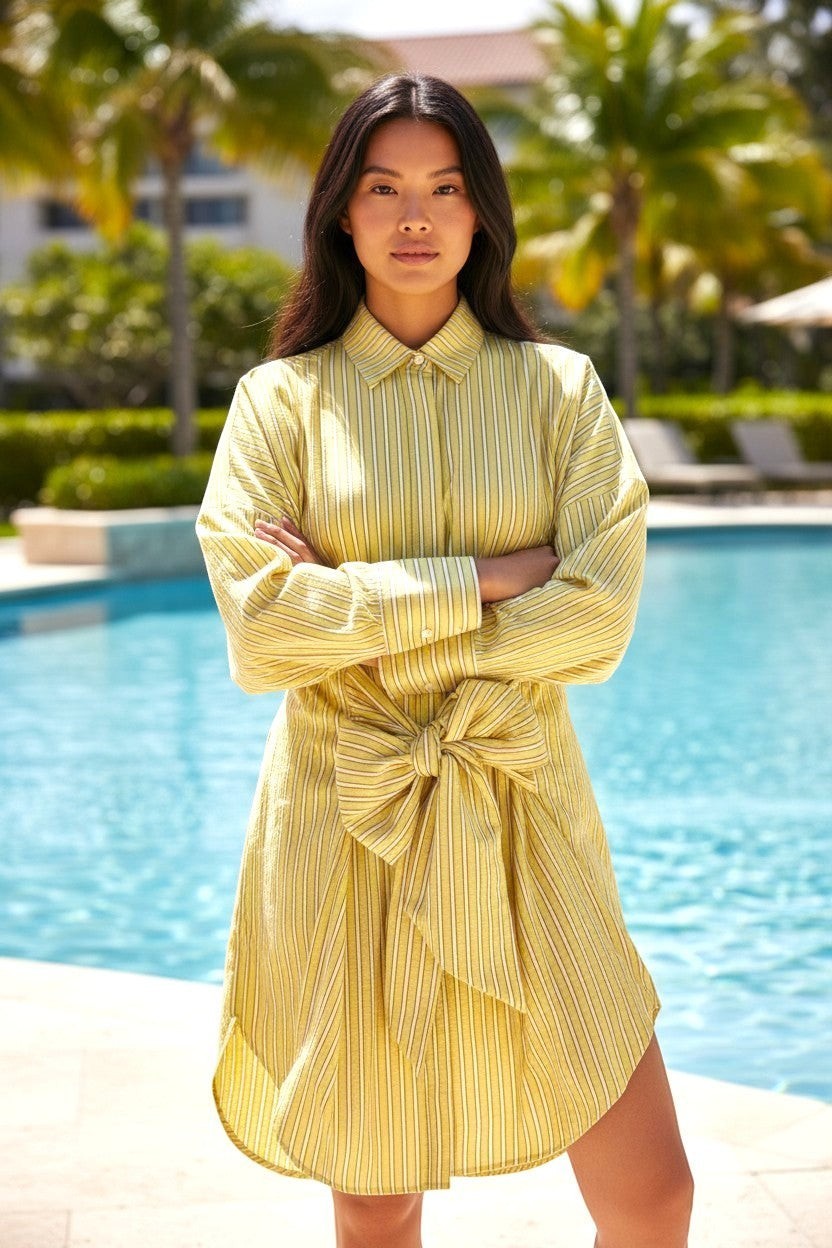State of Georgia yellow and white striped linen shirt dress with a tie waist, worn by a woman by a pool.